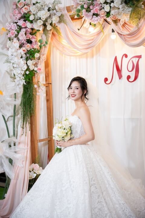 Cô dâu Trần Thuỳ đứng bên cổng hoa trong không gian tiệc cưới