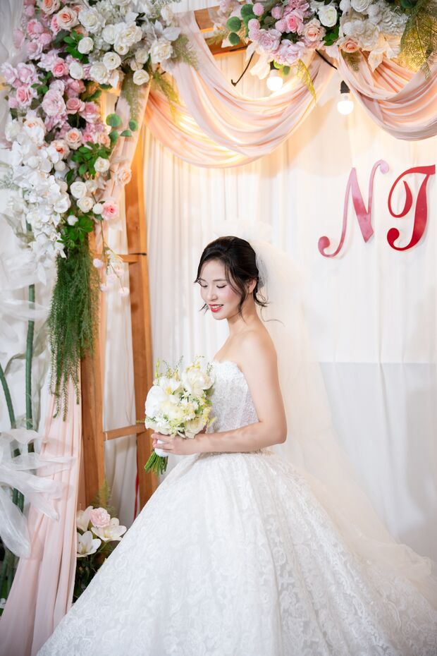 Cô dâu Trần Thuỳ đứng dưới cổng hoa trong ngày cưới